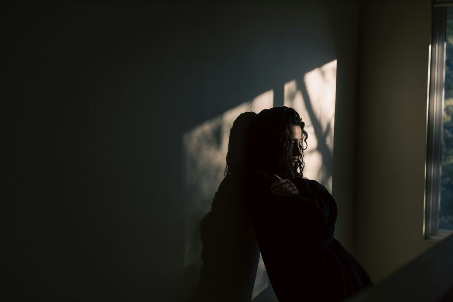 Person silhouetted by window, representing depression and isolation